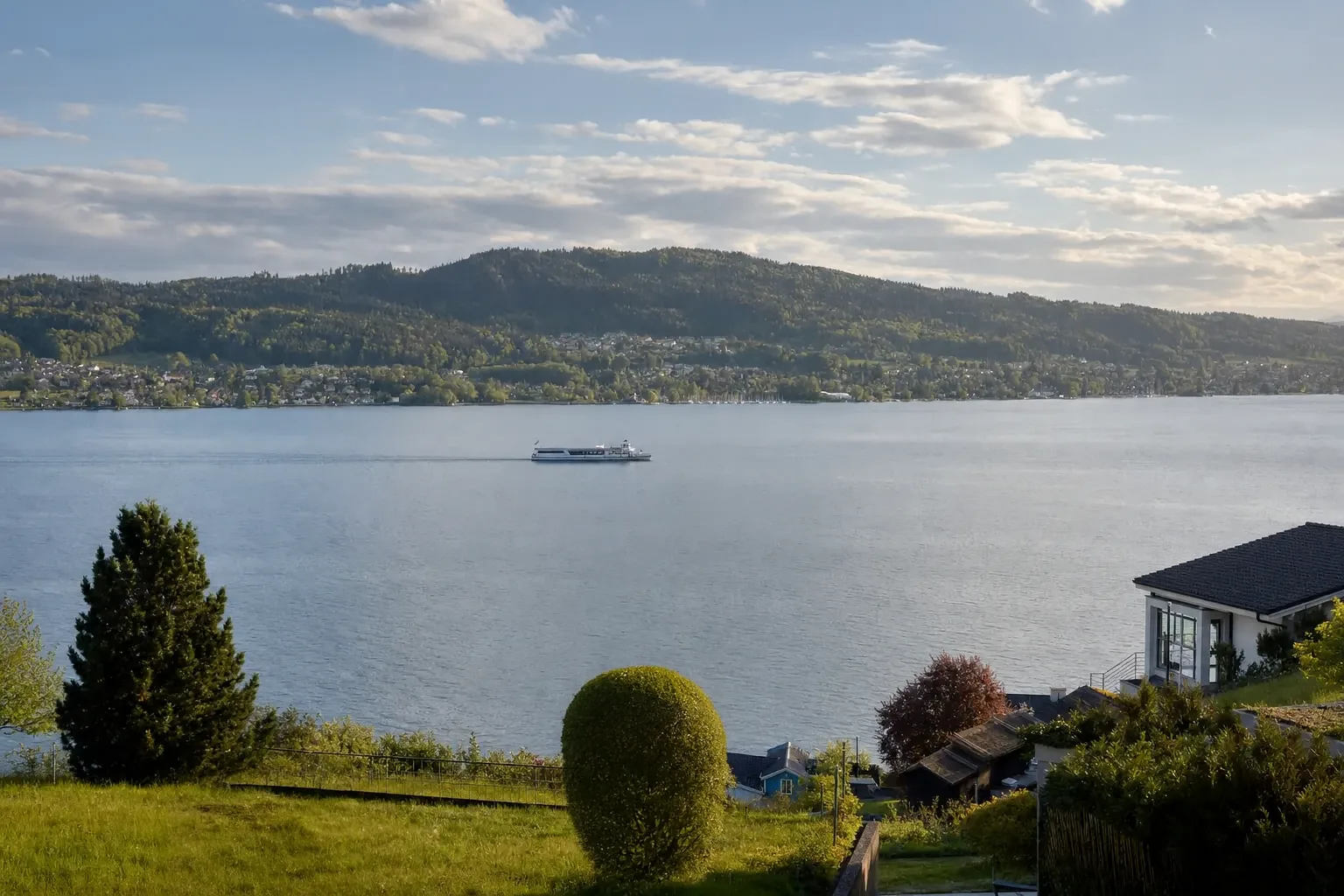 See mit Schiff und bewaldeten Ufern